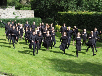 Die Mitglieder des Landesjugendchors Thüringen rennen lachend über eine Wiese. Alle tragen schwarze Sachen.
