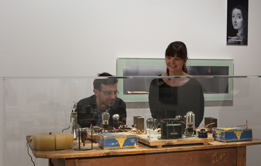 Das Bild zeigt zwei Besucher vor dem Arbeitstisch zur Uranspaltung von Lise Meitner.